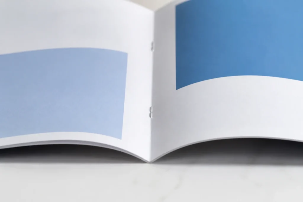 Close-up of wire staples along the centre fold of an open booklet.